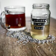 Lavender syrup for coffee with coffee cup behind it.