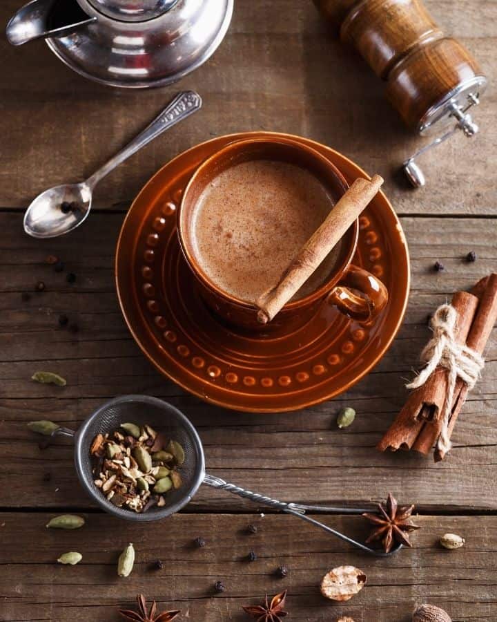 cup of chai tea on table with ingredients around it