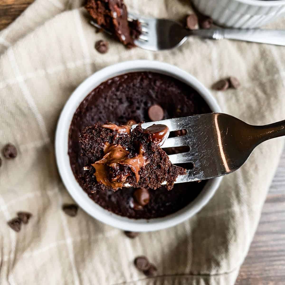 Top down pictures of vegan mug brownie. Fork holding a scoop of brownie with chocolate chips