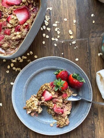 top down view of strawberry baked oatmeal. pan in one corner, and plate with oatmeal in center.