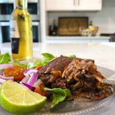 enchilada casserole on a plate with fixings. Fork scooping a bite out.