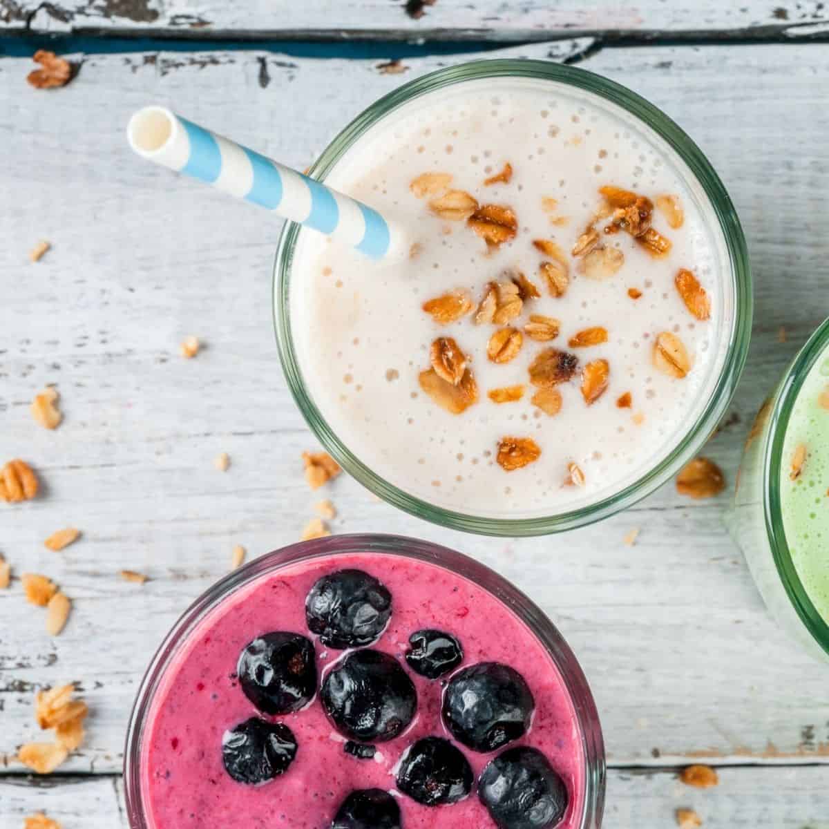 Top down view of a white smoothies topped iwth oats and a purple smoothies topped with blueberries