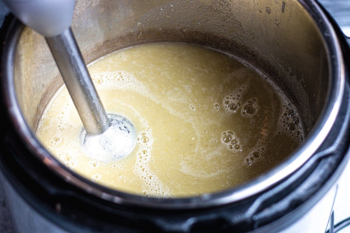 An immersion blender blending the asparagus soup in an instant pot. 