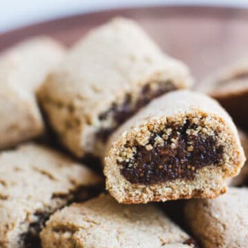 fig rolls- cookie crust with dark fig filling- piled high on top of a wooden plate.