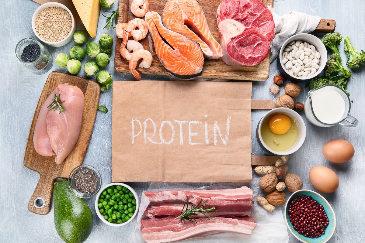 several protein foods surrounding a paper bag with the word "protein" on it. 