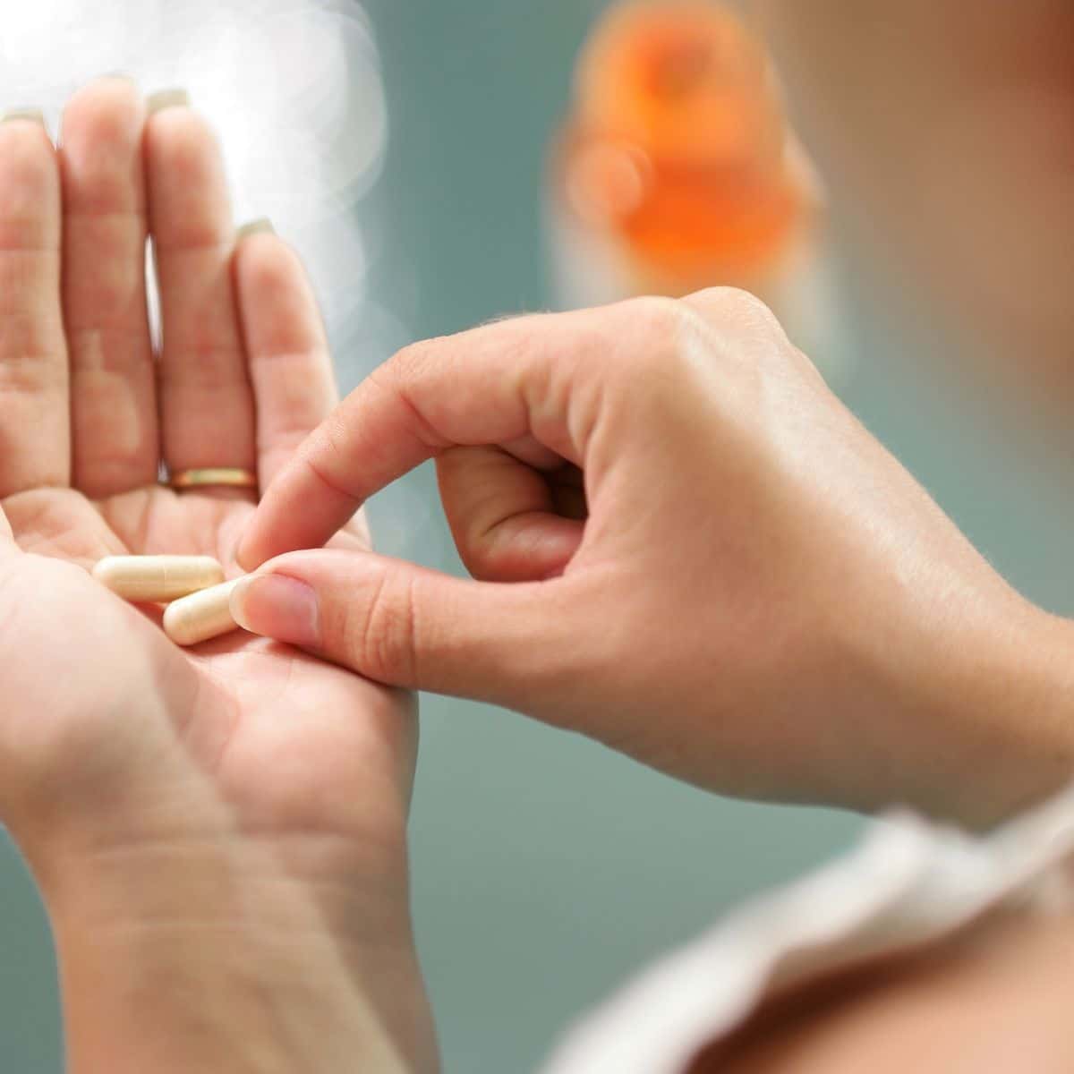 woman holding probiotics and prebiotics in her hand, taking them together. 