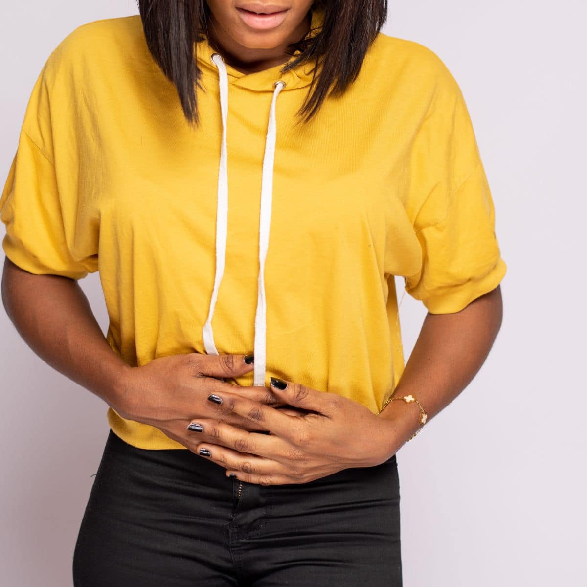 woman holding an aching stomach, a symptom of eating too much fiber. 