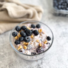 a bowl of blueberry overnight oats topped with blueberries and walnuts.