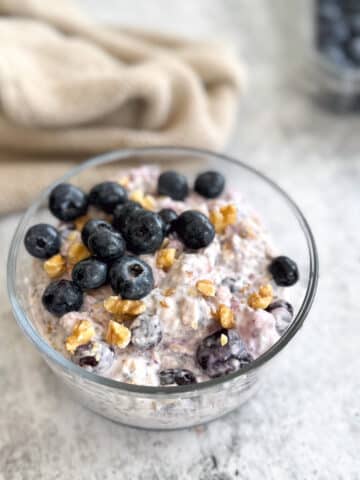 a bowl of blueberry overnight oats topped with blueberries and walnuts.