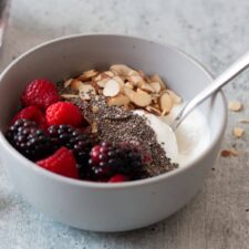 A bowl of blended cottage cheese topped with fruit and nuts.