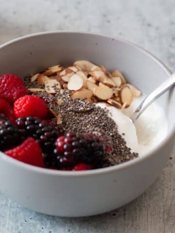 A bowl of blended cottage cheese topped with fruit and nuts.