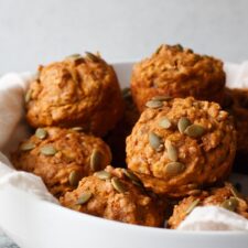 pumpkin banana bread muffins stacked in a bowl