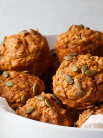pumpkin banana bread muffins stacked in a bowl