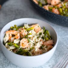 Lemon garlic rice bowl with shrimp and asparagus served in a white bowl, featuring tender shrimp, vibrant asparagus, and fragrant rice with a zesty garlic lemon touch.