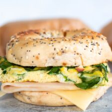 Healthy breakfast bagel sandwich with eggs, spinach, turkey, and melty cheese perfect for meal prep.