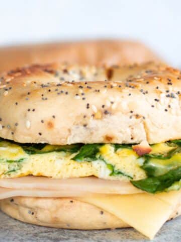 Healthy breakfast bagel sandwich with eggs, spinach, turkey, and melty cheese perfect for meal prep.