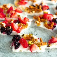 Frozen Greek Yogurt Bark with Berries topped with blueberries, strawberries, and crushed pretzels for a sweet, crunchy, quick high-protein snack.