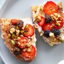 A quick and easy breakfast featuring ricotta and honey on toast, served on a white plate with fresh mixed berries for a balanced and nutritious meal.