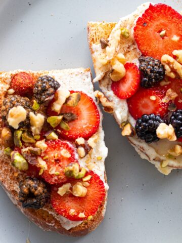 A quick and easy breakfast featuring ricotta and honey on toast, served on a white plate with fresh mixed berries for a balanced and nutritious meal.