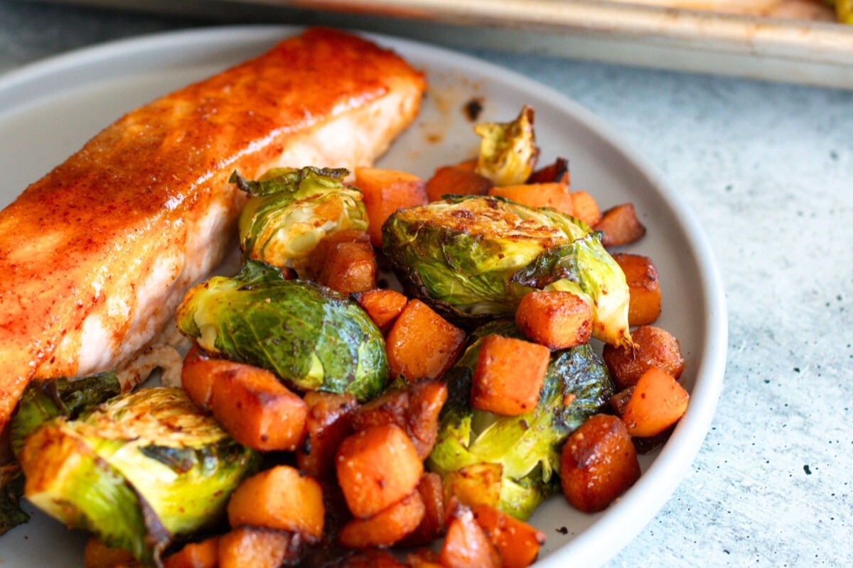 Sheet Pan Salmon with Veggies served on a plate with roasted butternut squash and Brussels sprouts—a nutritious, practical, and flavorful one-pan meal.