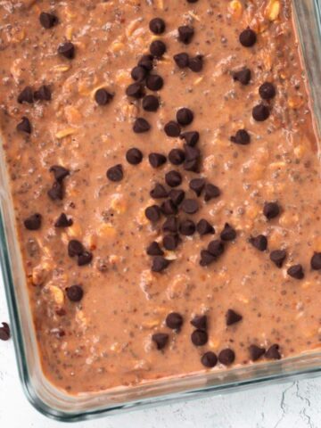 Chocolate protein overnight oats in a clear rectangular container, topped with chocolate chips, placed on a countertop.