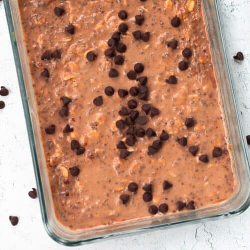 Chocolate protein overnight oats in a clear rectangular container, topped with chocolate chips, placed on a countertop.