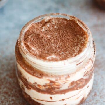 Tiramisu overnight oats in a jar with cocoa powder sprinkled on top.