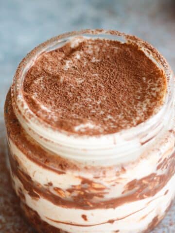 Tiramisu overnight oats in a jar with cocoa powder sprinkled on top.