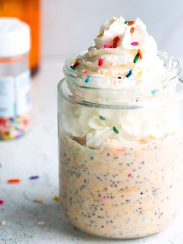 Birthday cake overnight oats in a glass jar topped with colorful sprinkles