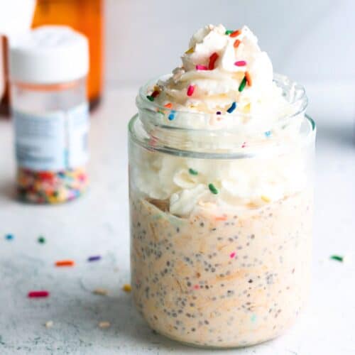 Birthday cake overnight oats in a glass jar topped with colorful sprinkles