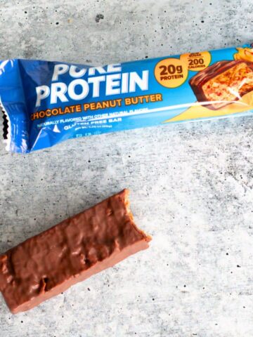 Pure Protein Chocolate Peanut Butter bar unwrapped on a table beside its blue wrapper. Are pure protein bars healthy?