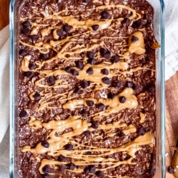 A bowl of chocolate peanut butter overnight oats topped with peanut butter drizzle and chocolate chips.