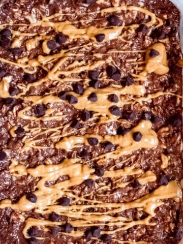 A bowl of chocolate peanut butter overnight oats topped with peanut butter drizzle and chocolate chips.