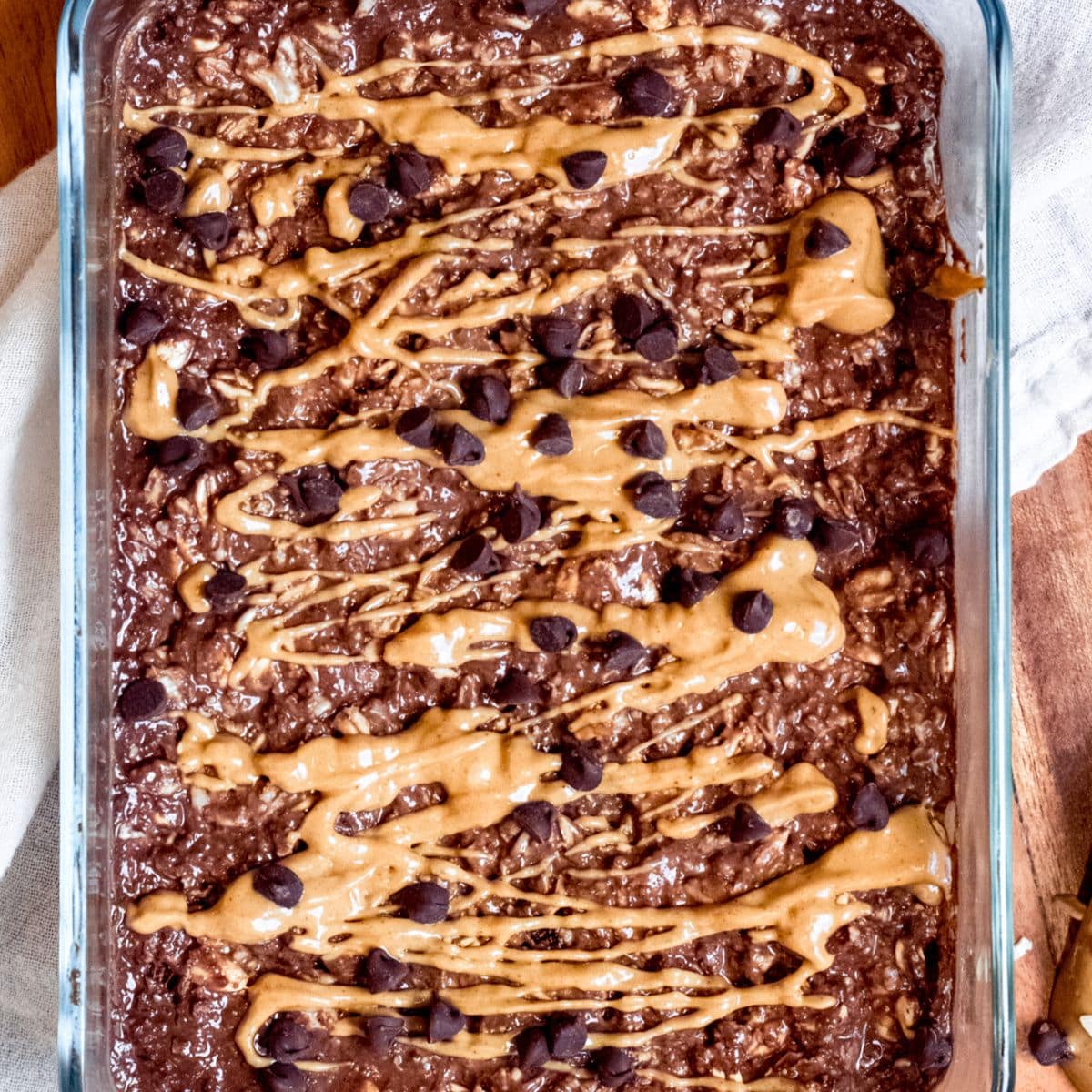 A bowl of chocolate peanut butter overnight oats topped with peanut butter drizzle and chocolate chips.